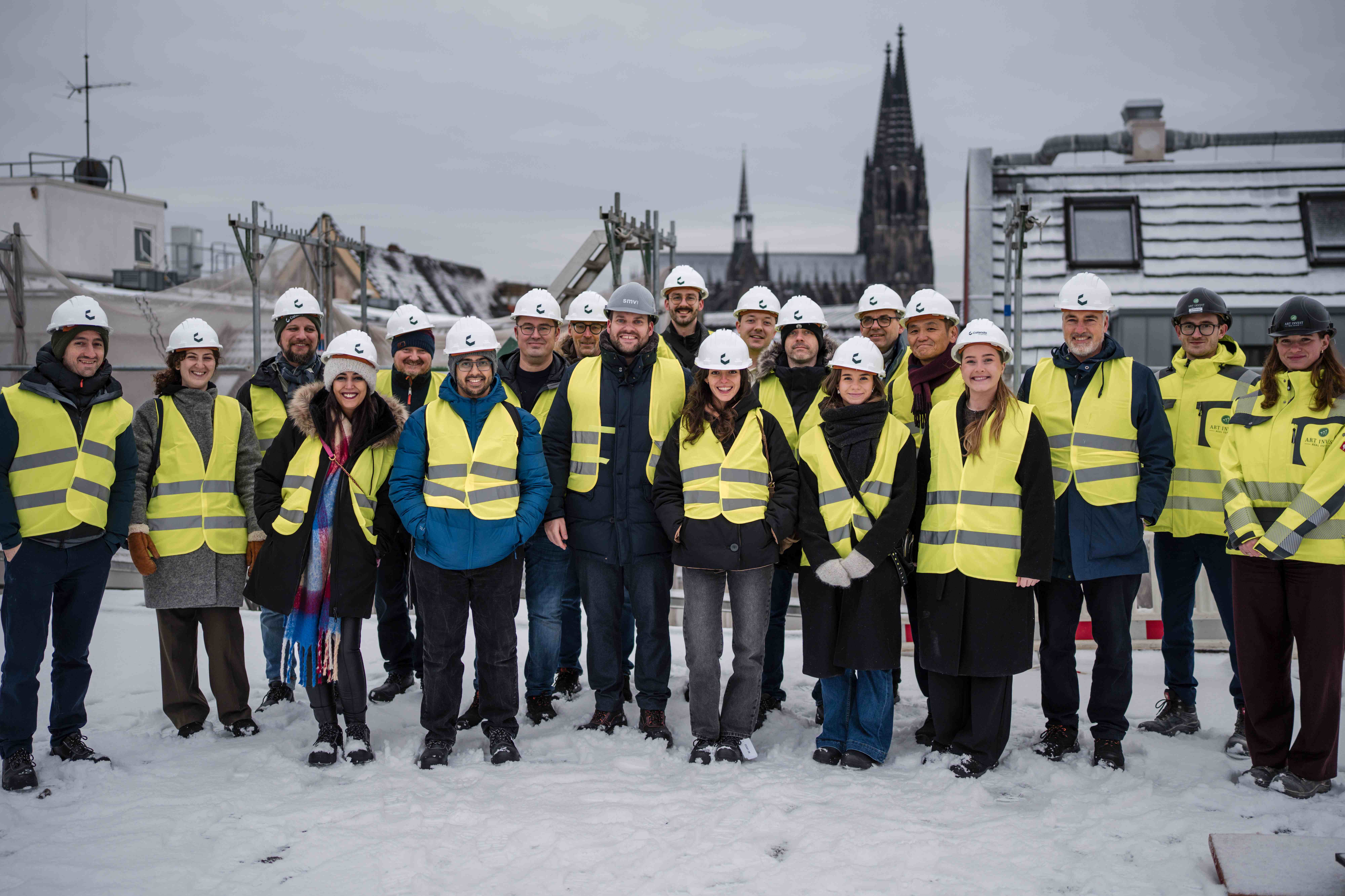 The Catenda team wearing hi-vis vests and Catenda hard hats on a snowy rooftop with Cologne Cathedral in the background