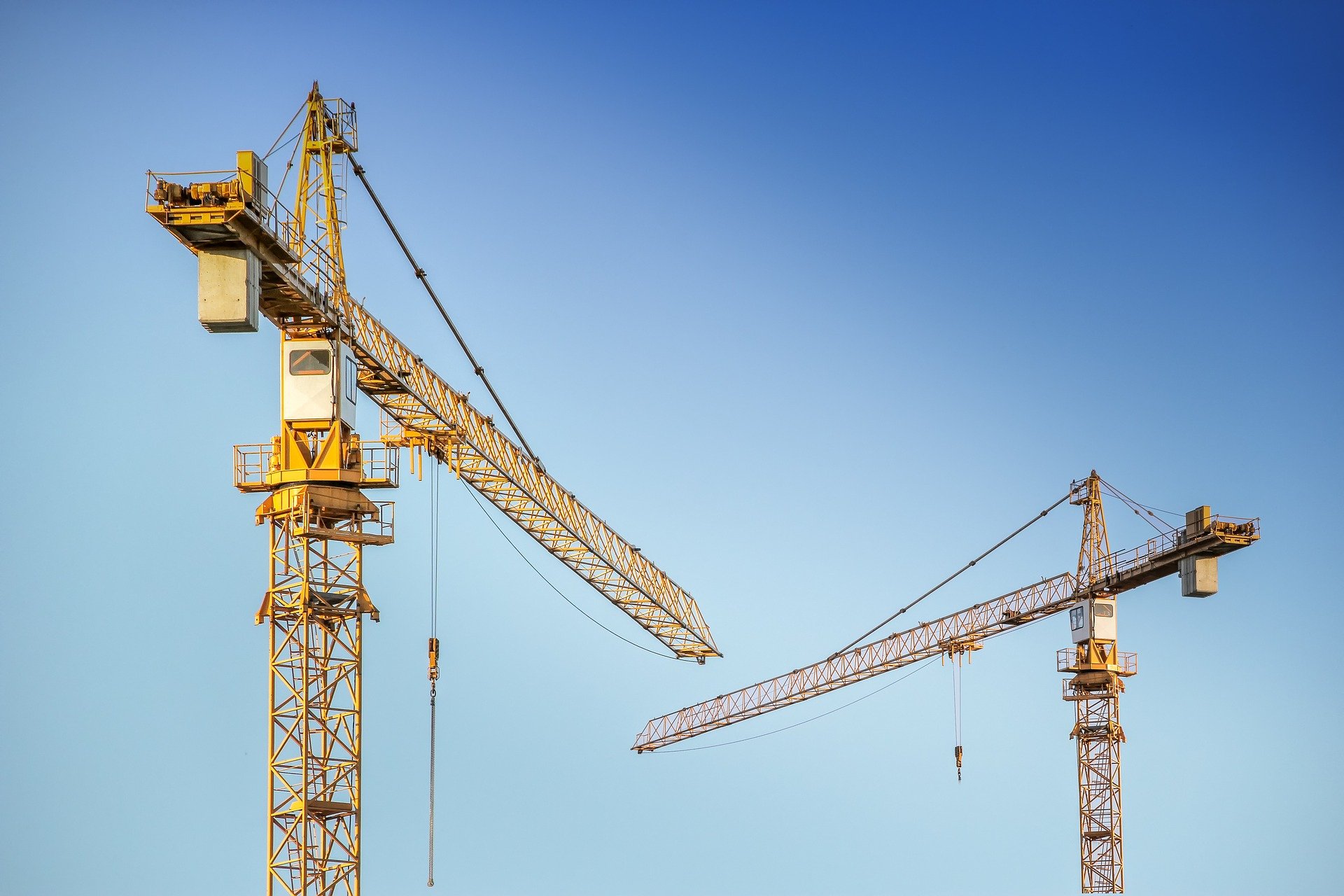 2 yellow cranes with blue cloudless sky as background