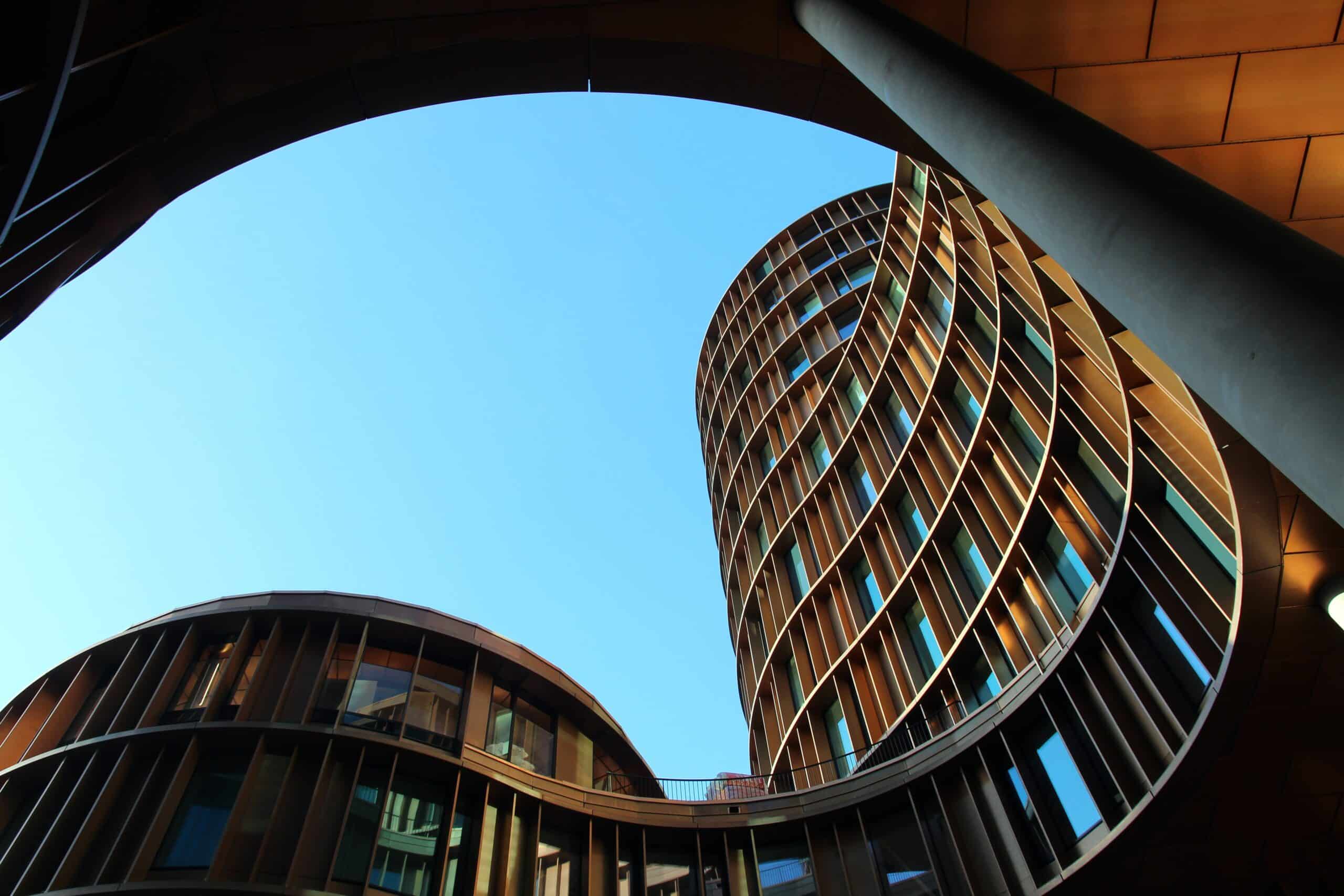 shot from the ground looking up to some round / curved modern buildings with big windows