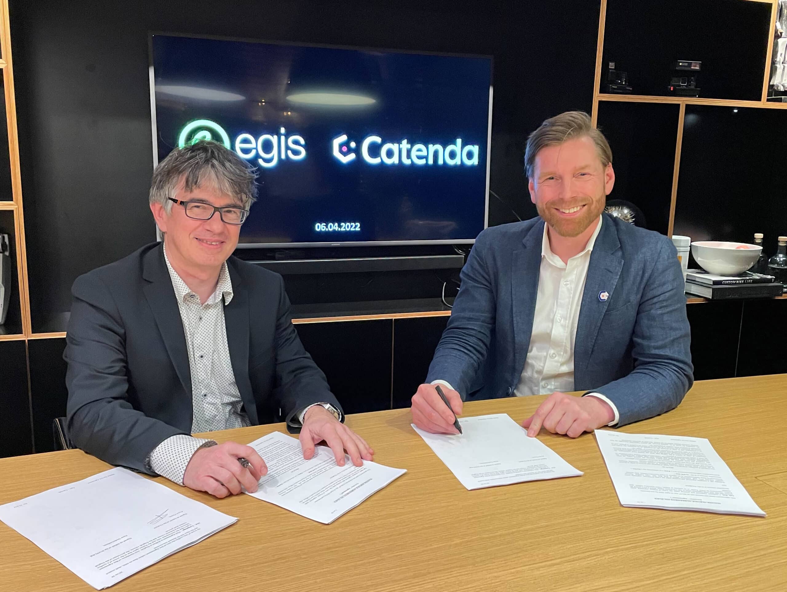 Egis representatnt and Catenda CEO Einar Gudmundsson sign contract, sitting and smiling in the camera, having their logos in the back
