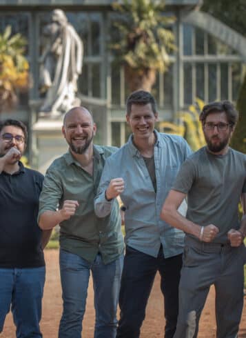 Dev team standing together, making a fist and smiling at the camera