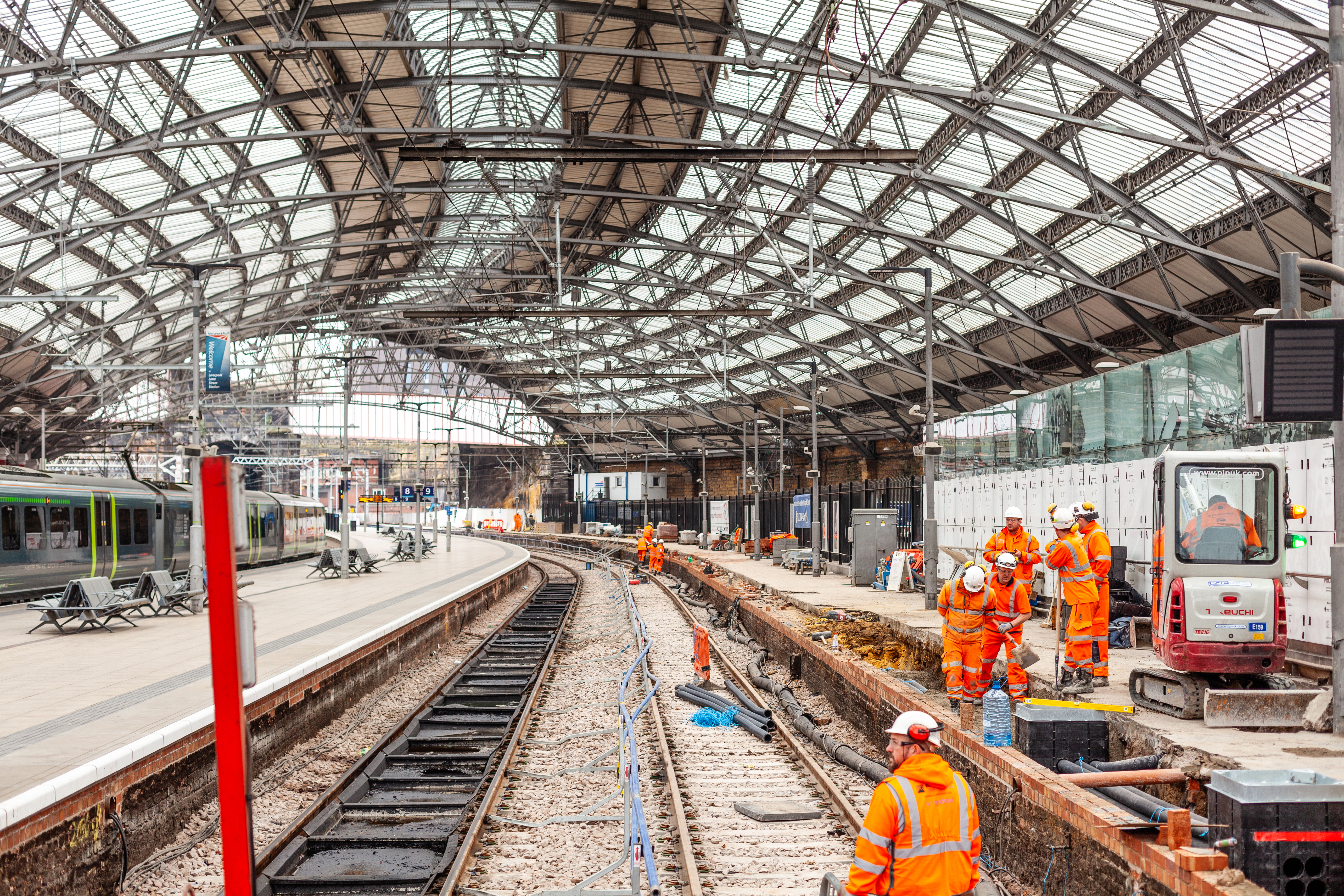 Liverpool, UK - April 11, 2018: A team of rail track maintenance workers inspecting and repairing a railway track while a train passes by during the day in Liverpool Lime Street Station