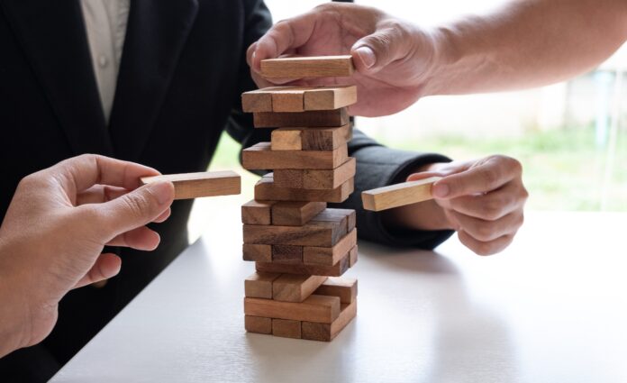 Two hands playing blocks wood game, placing wooden block. Concept Risk of management and strategy plan, growth business success process and team work.