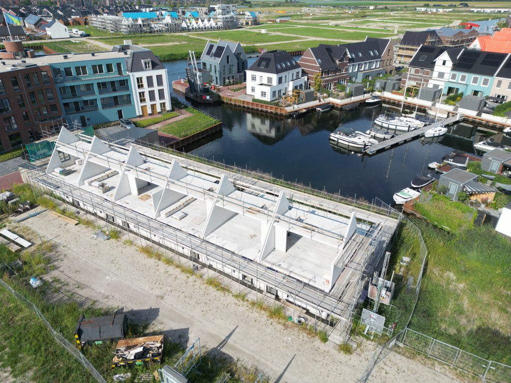Aerial drone photo of a waterfront residential construction project in Zeewolde Boeghaven with exposed concrete roof structures and a marina in the background