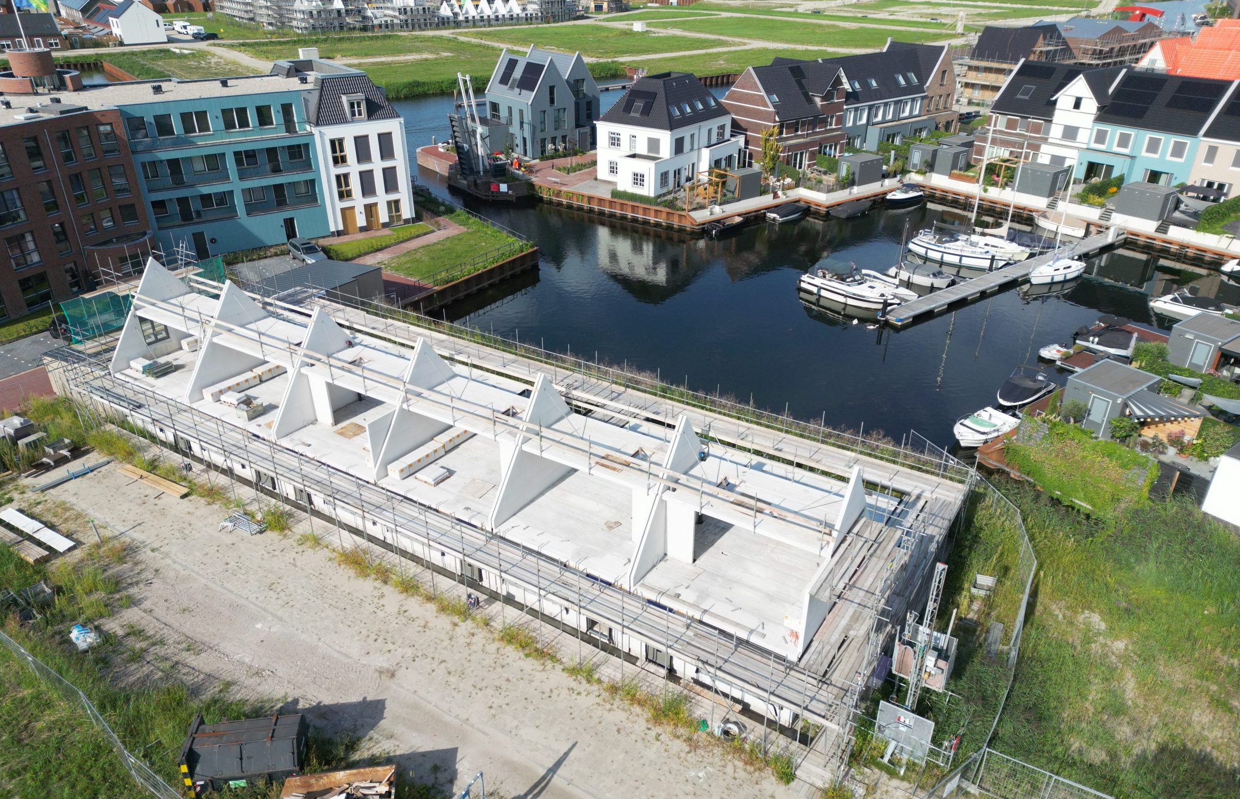 Aerial drone photo of a waterfront residential construction project in Zeewolde Boeghaven with exposed concrete roof structures and a marina in the background